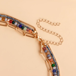 Dettaglio della collana bohémien a più strati con perline colorate e catene dorate