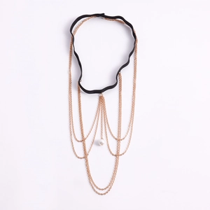 Dettaglio della catena da gamba dorata con frange e perla su fascia elastica nera
