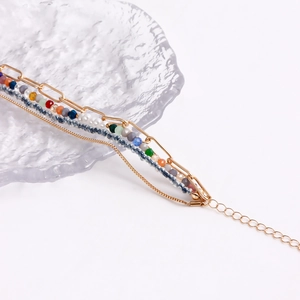 Dettaglio di un bracciale boho multistrato con perline colorate e catene dorate