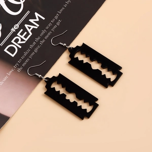 Close-up of black acrylic blade earrings with hollow design on orange background