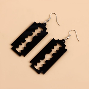 Detailed close-up of black acrylic blade earrings with silver hooks in punk style