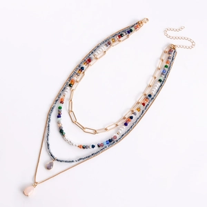 Dettaglio di collana boho a strati con perline colorate e ciondoli a forma di goccia d'acqua