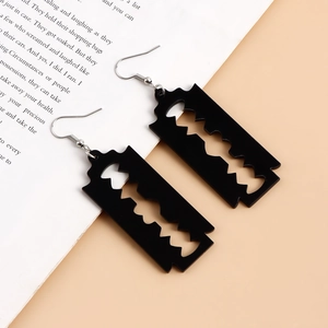 Close-up of black acrylic razor blade earrings on a vintage book page background