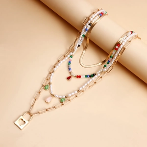 Dettaglio di collana bohémien a strati con lucchetto a cuore, perle e perline colorate