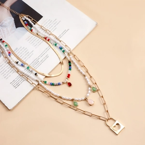Dettaglio di una collana boho a strati con perline colorate e ciondolo a lucchetto a cuore