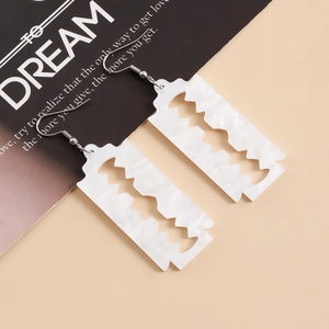 Macro shot of white marble texture acrylic razor blade earrings with silver metal hooks
