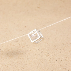 Detailed view of square silver pendant with clear cubic zirconia on an invisible chain