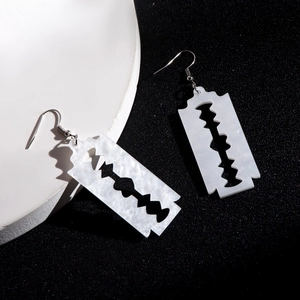 Detailed macro view of black acrylic razor blade earrings with marble texture and silver hooks