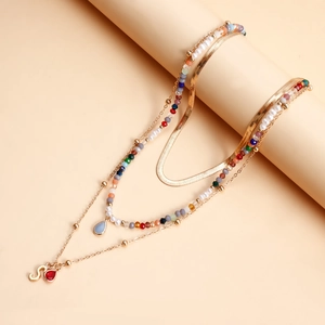 Dettaglio della collana multistrato con catena a serpente dorata, perline e ciondoli