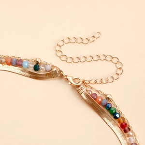 Dettaglio macro della collana bohémien a più strati con perline colorate e catena oro