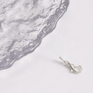 Macro shot of silver lobster clasp on transparent necklace wire with smooth metallic finish