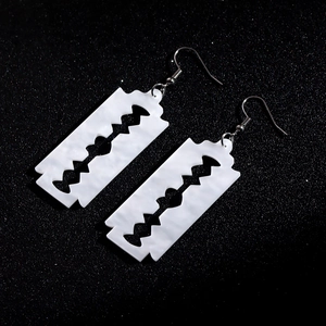 Macro shot of creative blade shaped acrylic earrings with hollow punk gothic style design