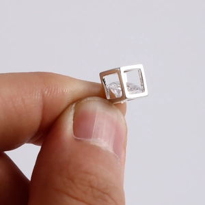Macro detail of a minimalist silver cube pendant with a floating zircon crystal gem