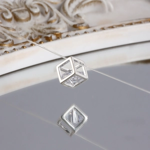 Macro view of geometric cube pendant with zircon stone on a transparent line over a mirror