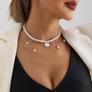 Detail van elegante parelchoker met hartvormige hanger en kwastjesfranje op het model