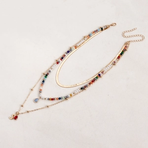 Dettaglio della collana boho a strati con perline colorate e ciondolo a goccia rosso