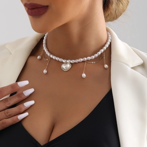 Detail van vintage parelketting met hartje, gouden kwastjes en strass accenten