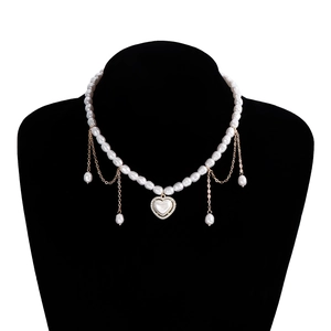 Detail van vintage parelketting met hartvormige hanger, gouden kwastjes en zirkoon