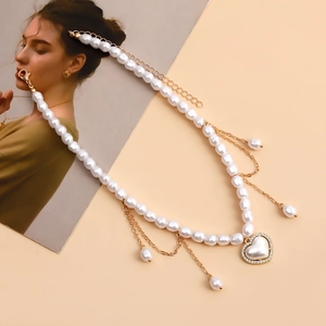 Detail van elegante parelketting met hartvormige hanger en goudkleurige kwastjes