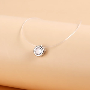 Detailed view of single round zircon pendant on invisible clear nylon fish line necklace