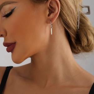 Gros plan d'une boucle d'oreille anneau argentée avec pendentif barre verticale