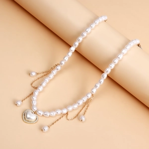 Gedetailleerd beeld van de parelketting met hartvormige hanger en gouden kwastjes