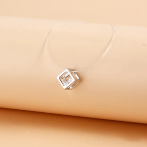 Close-up of a silver geometric cube pendant with clear zircon on transparent fishing line