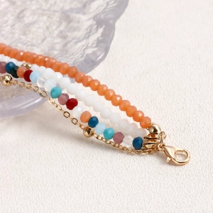 Dettaglio macro di una collana bohémien multistrato con perle di cristallo e catena d'oro