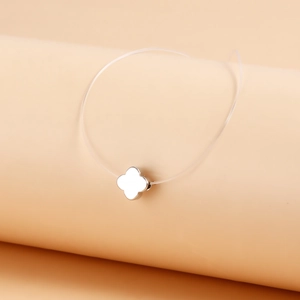 Detail of silver clover pendant on invisible string with minimalist polished finish