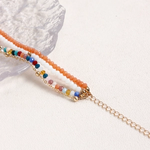 Dettaglio della collana bohémien a più strati con perline colorate e catena dorata