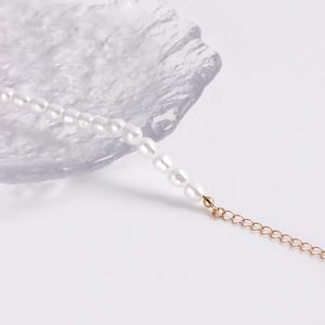 Detail van witte parelketting met gouden verlengketting en kleine metalen kraal