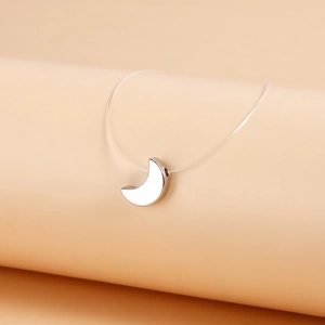 Close-up of polished silver crescent moon pendant on invisible nylon wire necklace