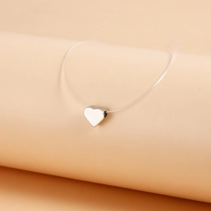 Detail of a silver heart pendant on a transparent fishing line for an invisible floating effect