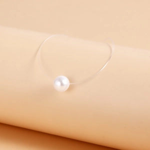 Detail of single white pearl pendant on minimalist invisible transparent fishing line