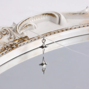 Close-up of a silver four-point star pendant on a clear cord with elegant mirror reflection
