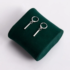 Boucles d'oreilles créoles argentées avec pendentif barre sur velours vert foncé