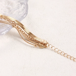 Dettaglio di un bracciale dorato multistrato con catena a serpente, perline e estensione