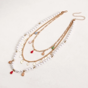 Dettaglio della collana boho multistrato con ciondoli a goccia colorati e charms stella e luna