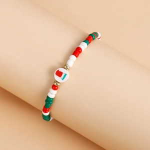 Detail of Christmas beaded bracelet with red, white, green beads and festive magnetic charm