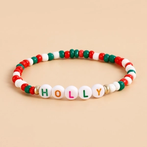 Macro detail of Christmas beaded bracelet featuring green red beads and HOLLY letter charms