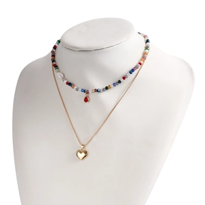 Dettaglio della collana boho multistrato con perline colorate e ciondolo a cuore d'oro