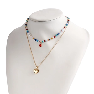 Dettaglio della collana bohémien a due strati con perline colorate e ciondolo a cuore d'oro