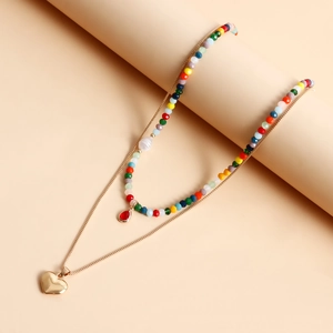 Dettaglio collana bohémien a strati con perline colorate e pendente a cuore dorato