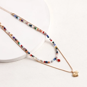 Dettaglio della collana boho a strati con perline colorate e ciondolo a cuore dorato