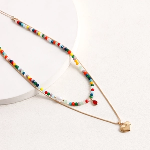 Dettaglio di collana boho a strati con perline colorate e ciondolo a cuore dorato