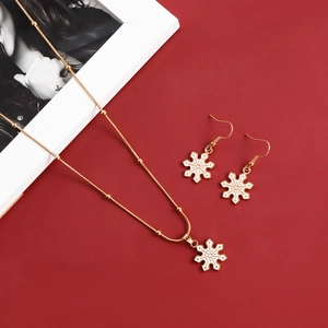 Detail of gold snowflake jewelry set with white enamel necklace and drop earrings