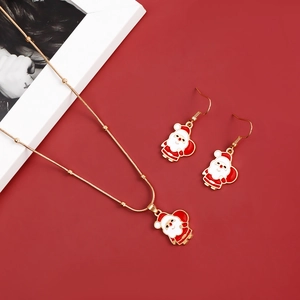 Close-up of golden Christmas Santa necklace and earrings set on festive red background