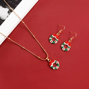 Detail of Christmas wreath necklace and earrings set with red bows on red background