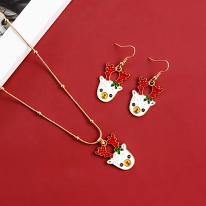 Detailed view of Christmas reindeer necklace and earrings set on a festive red background