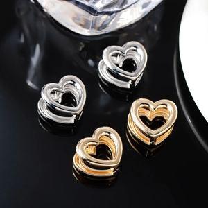 Macro di orecchini a cuore cavo in oro e argento lucido su base a specchio elegante